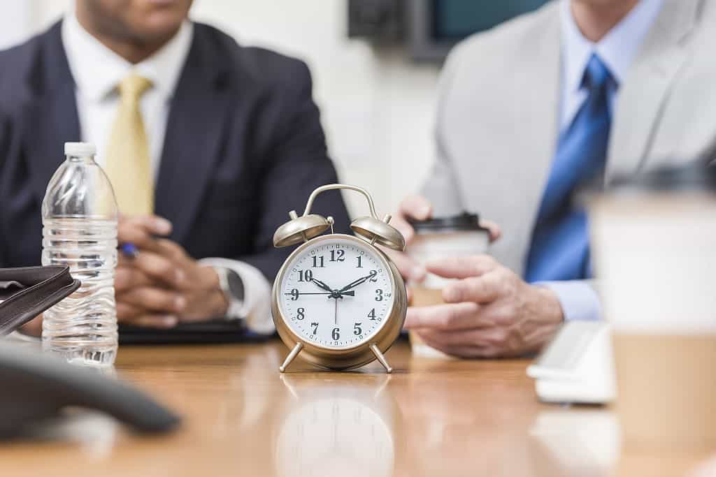 Clock on table in front of businessmen